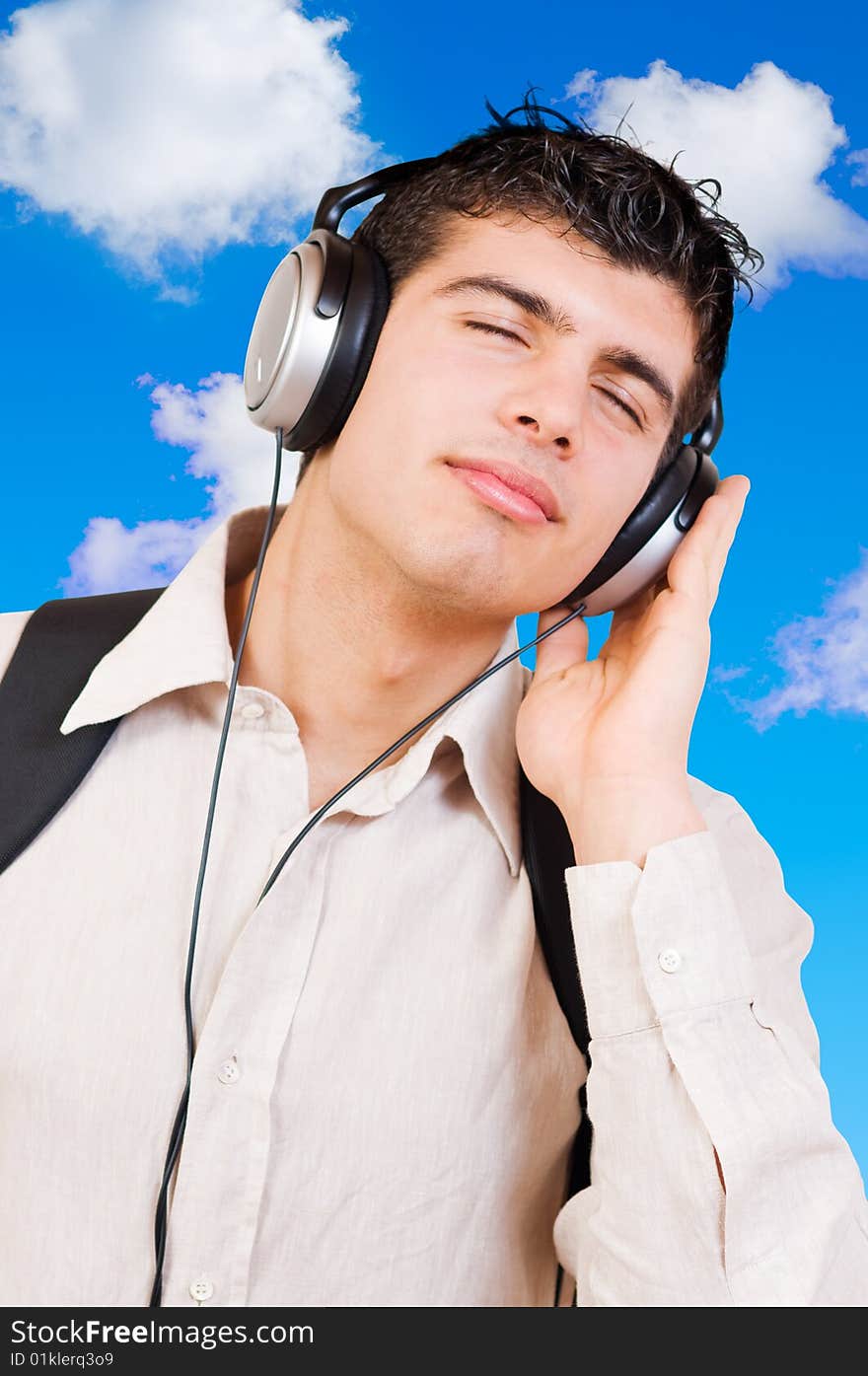 Portrait of young man listening music in headphones with great pleasure outdoor