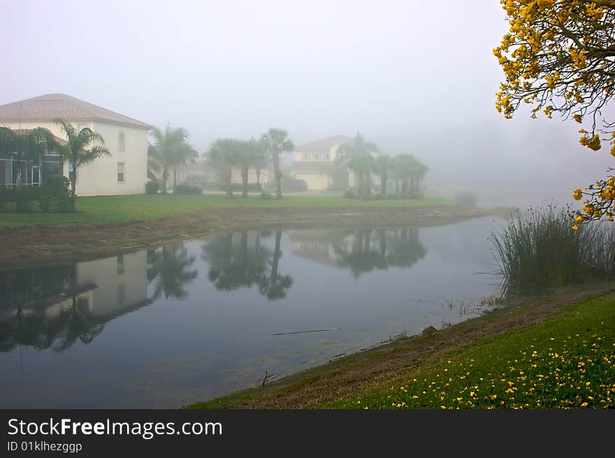 Foggy morning in florida showing lake front homes reflected in water