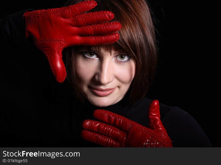 Woman looking straight from dark. In front of her red gloves on her hands. Horizontal