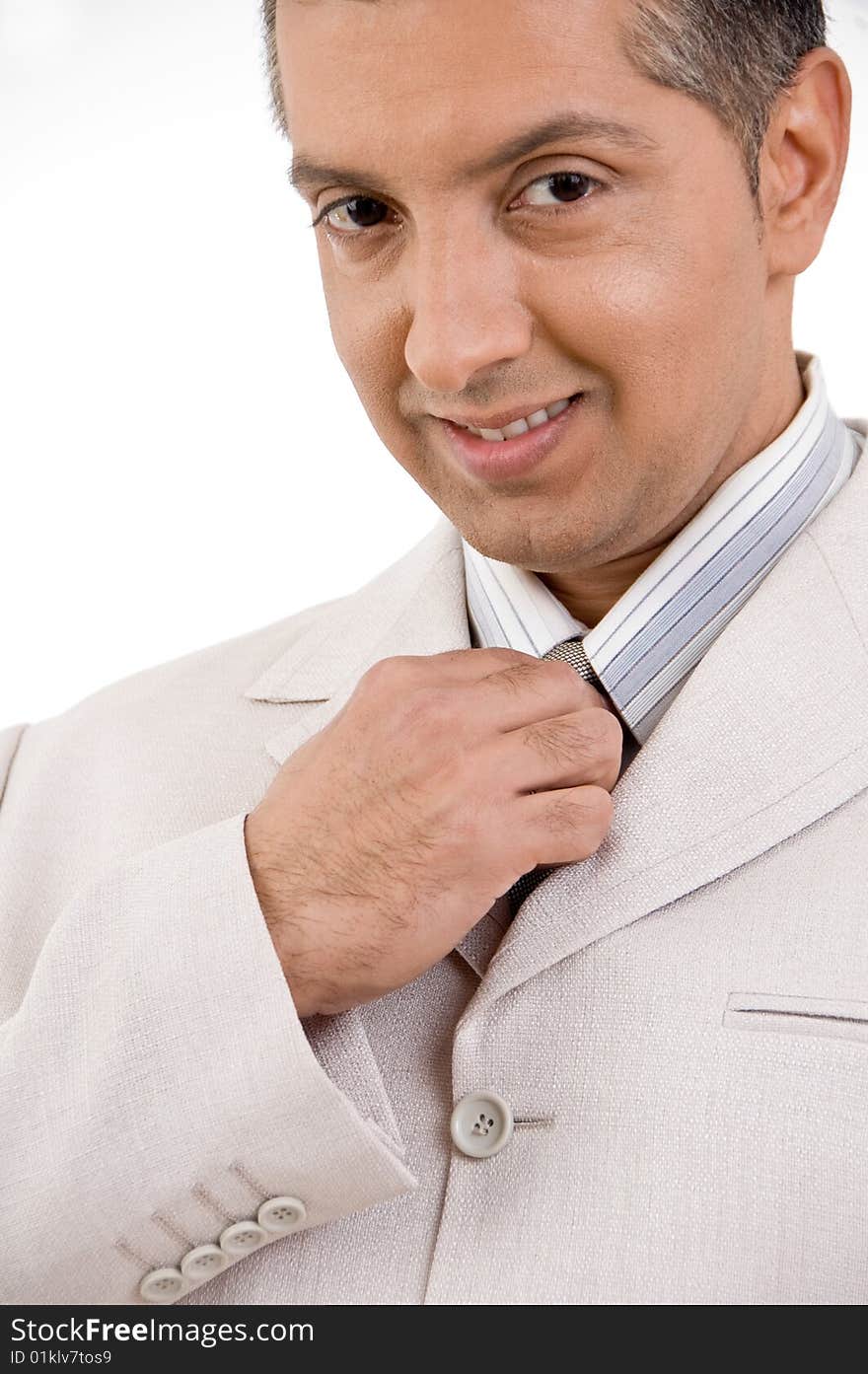 Close view of smiling businessman holding tie with white background