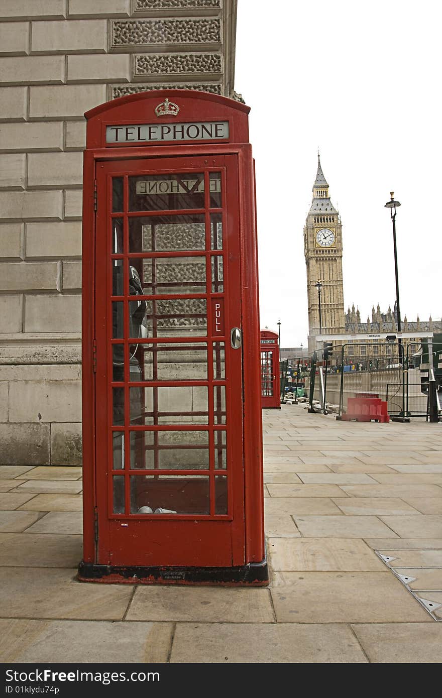 The famous Big Ben with a traditional telephone booth in front of it. The Big Ben is located in London England.