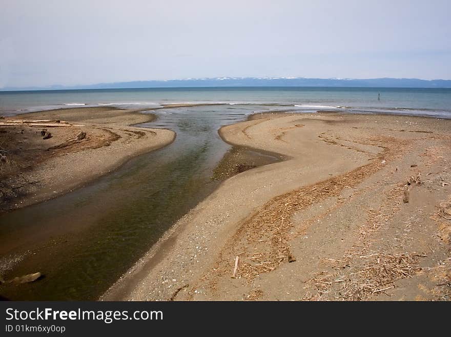 The mouth of a small river opening up into Puget Sound, Washington, with Victoria Island, Canada in the distance. The mouth of a small river opening up into Puget Sound, Washington, with Victoria Island, Canada in the distance.