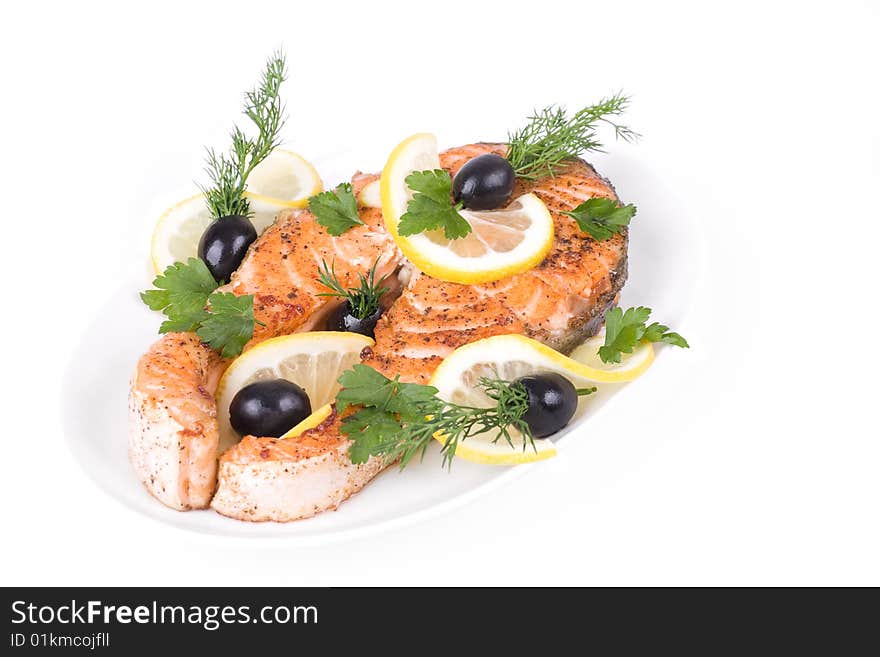 Appetizing Grilled Salmon with lemon, black olives and mixed greens isolated over white