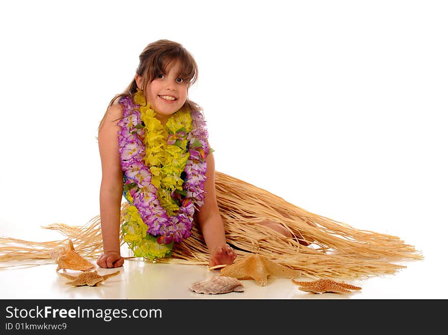 A happy elementary girl relaxing in her grass skirt and leis.  Isolated on white. A happy elementary girl relaxing in her grass skirt and leis.  Isolated on white.