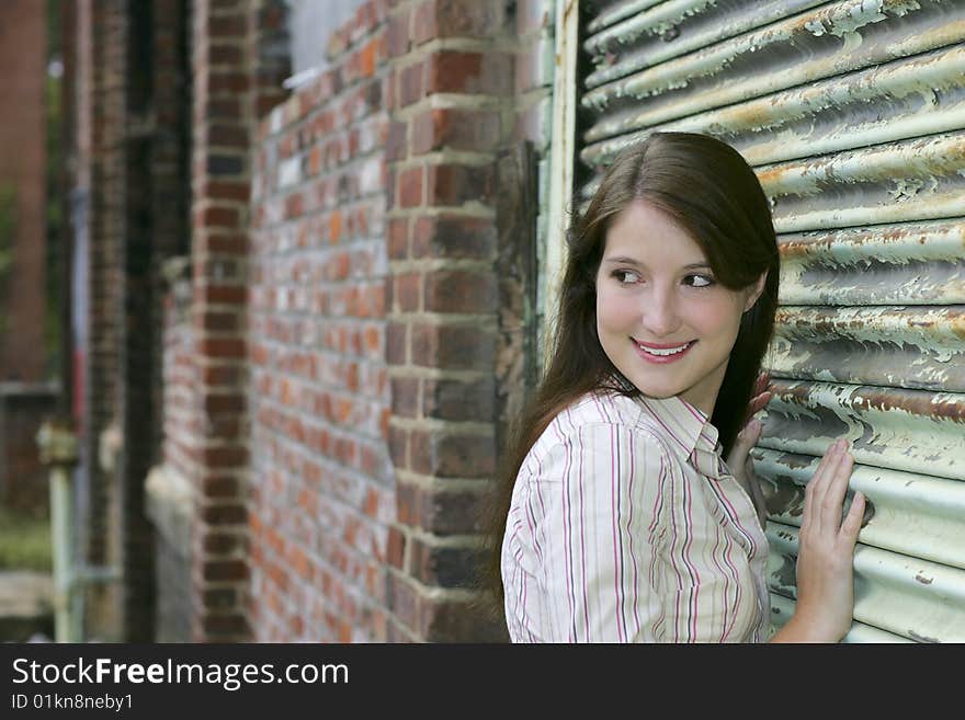 One beautiful twenties woman with long dark hair against a rusted metal door grungy portrait outdoors. One beautiful twenties woman with long dark hair against a rusted metal door grungy portrait outdoors