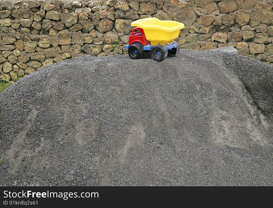 One red blue and yellow young child's toy truck on a sand pile