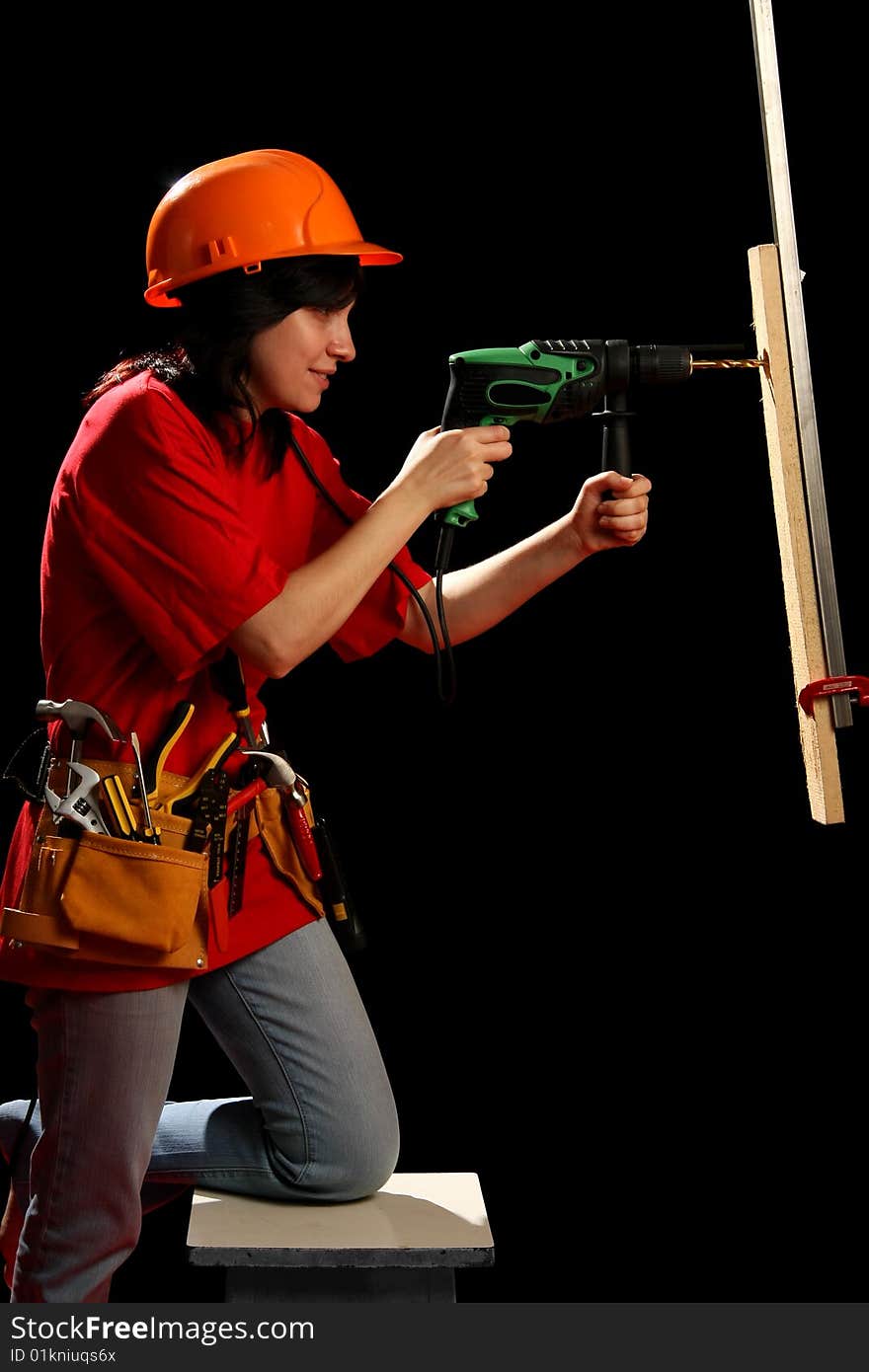 Young woman with work tools and drill, isolated on black