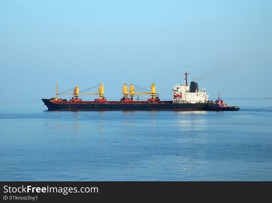 Container ship coming into port with tugboats