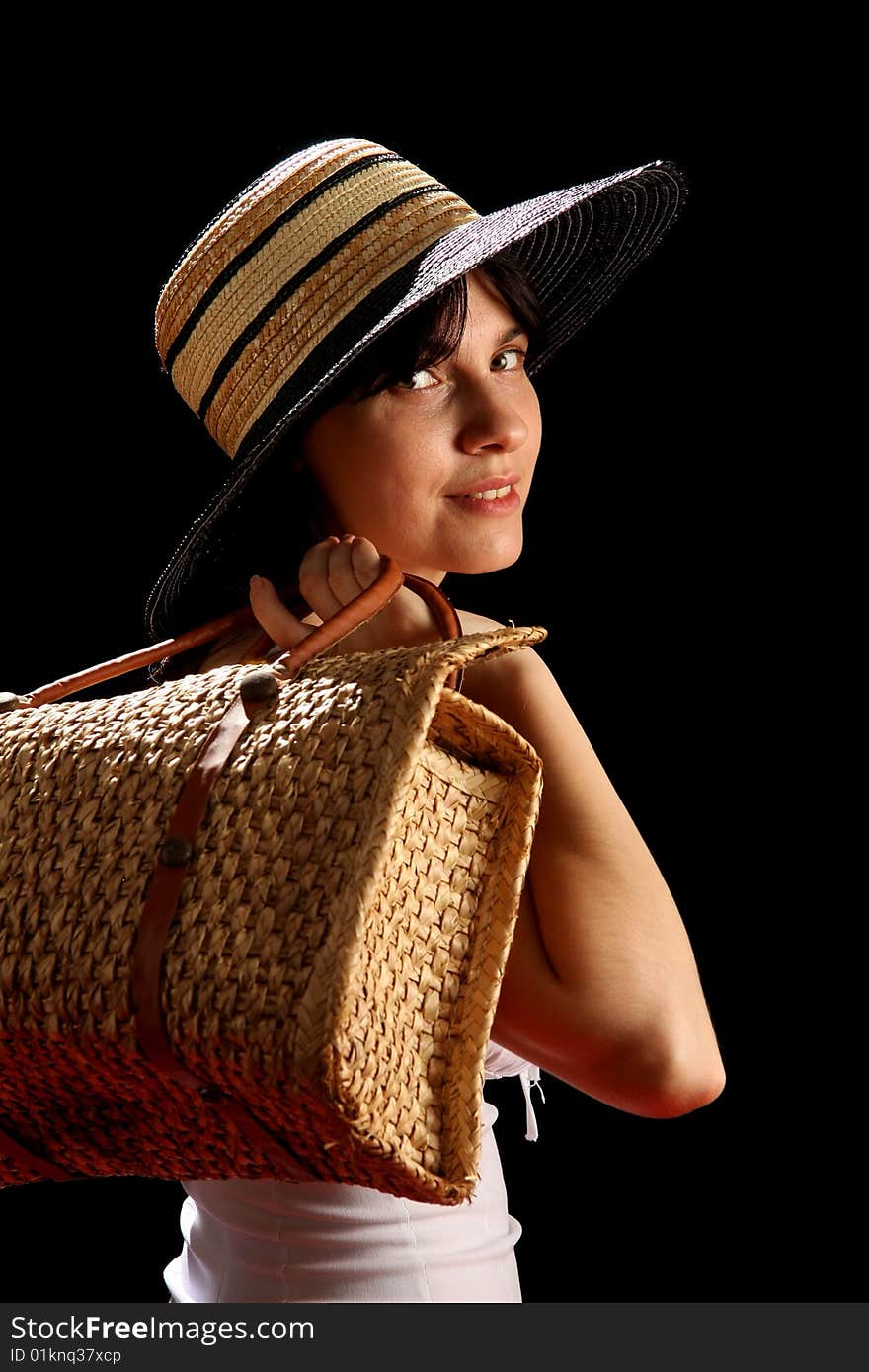 Young woman with straw hat and bag, isolated on black