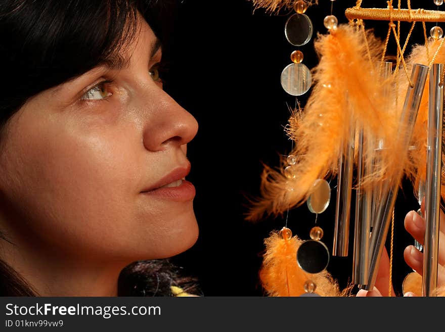 Young brunette and wind chime, on black background