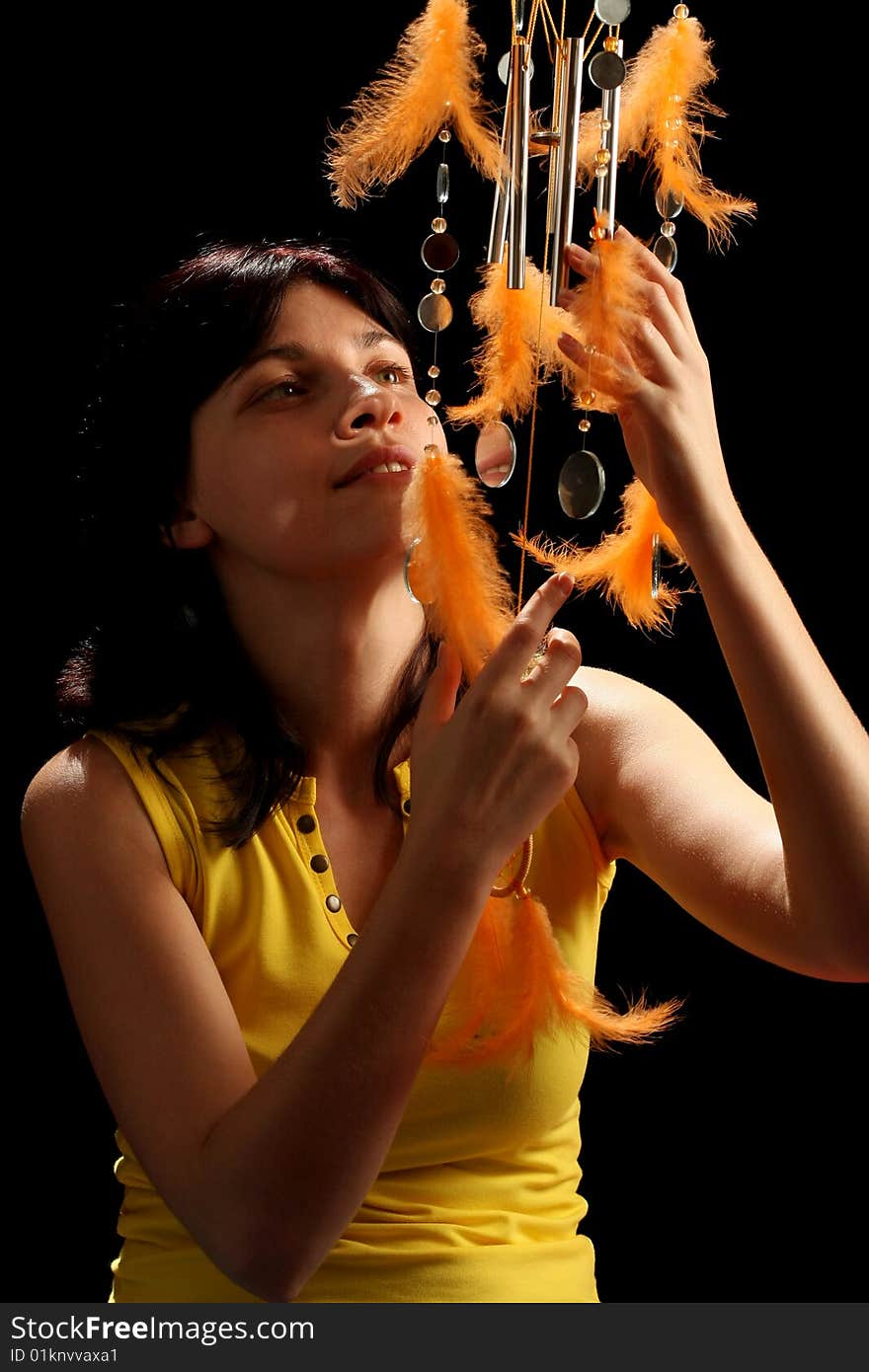 Young brunette and wind chime, on black background