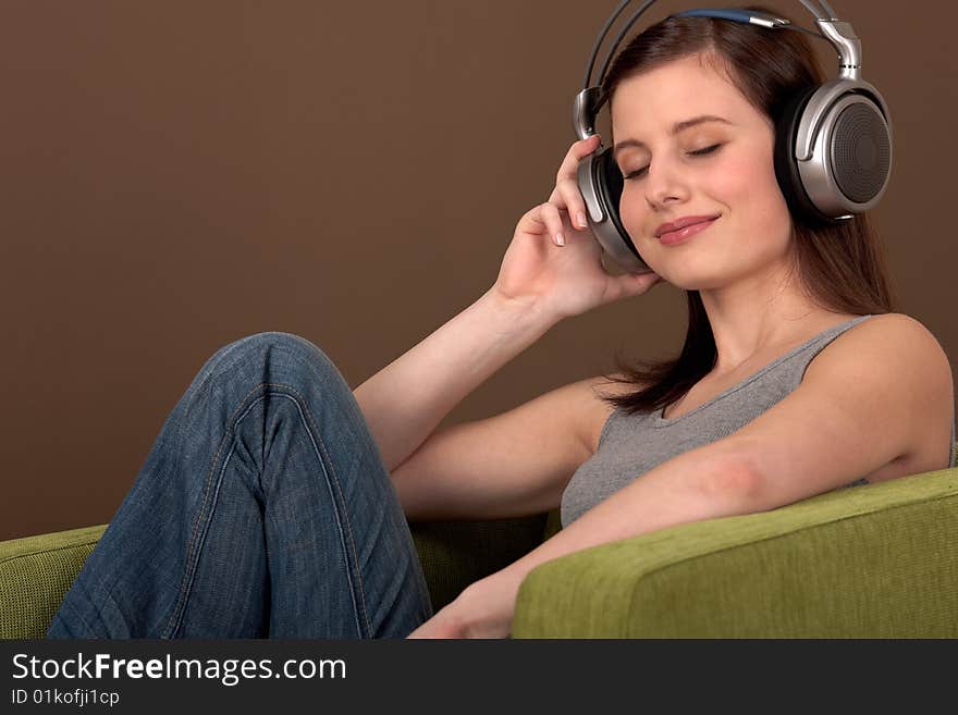 Young brown hair woman listening to music sitting on green armchair. Young brown hair woman listening to music sitting on green armchair