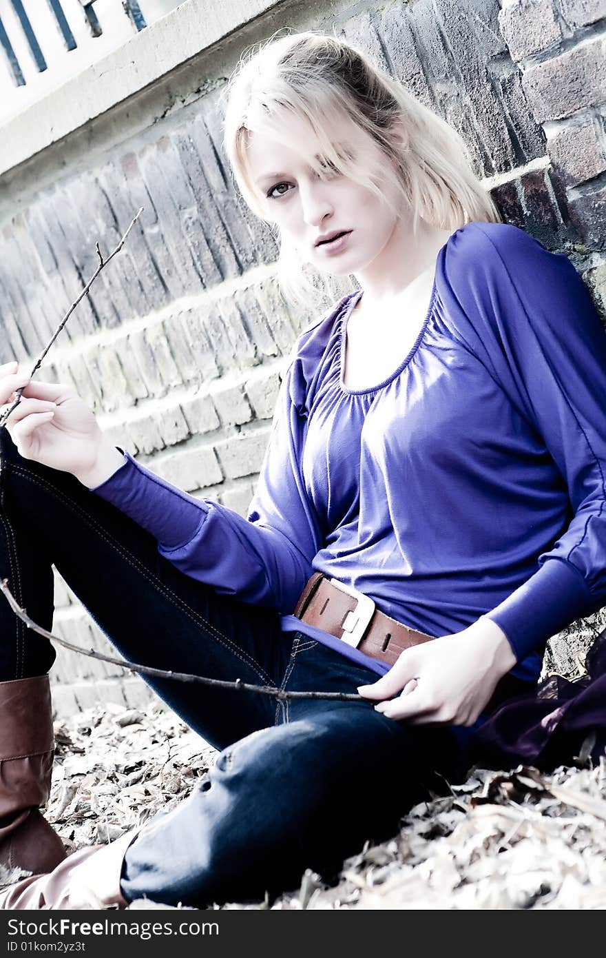 Young blond girl outside on a street posing against the wall. Young blond girl outside on a street posing against the wall