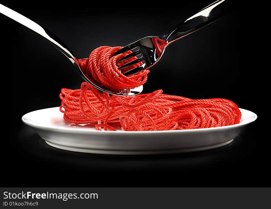 The red rope on a white plate, rolled up on a fork