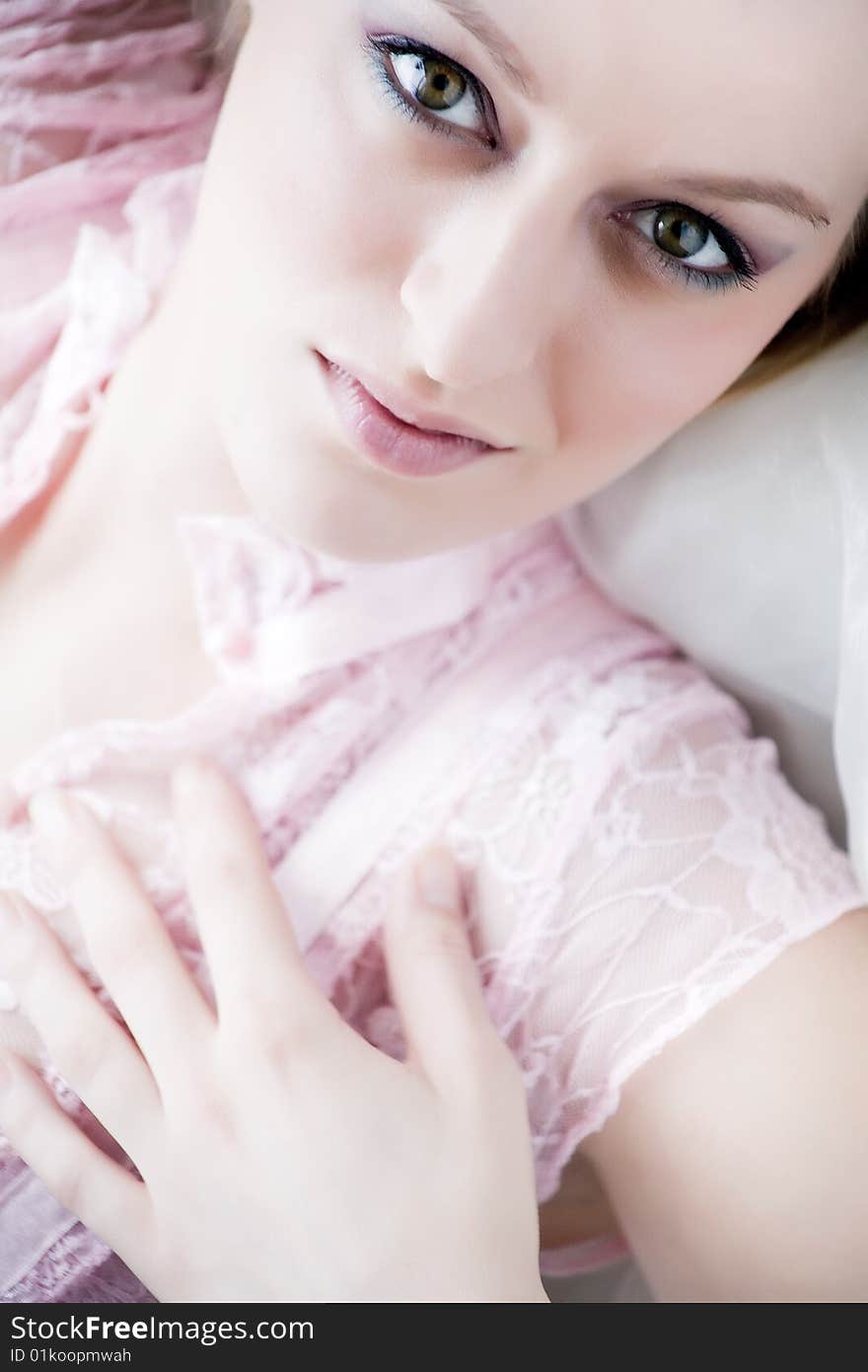 Young blond girl posing in light pink lingerie nearby a bright window. Young blond girl posing in light pink lingerie nearby a bright window