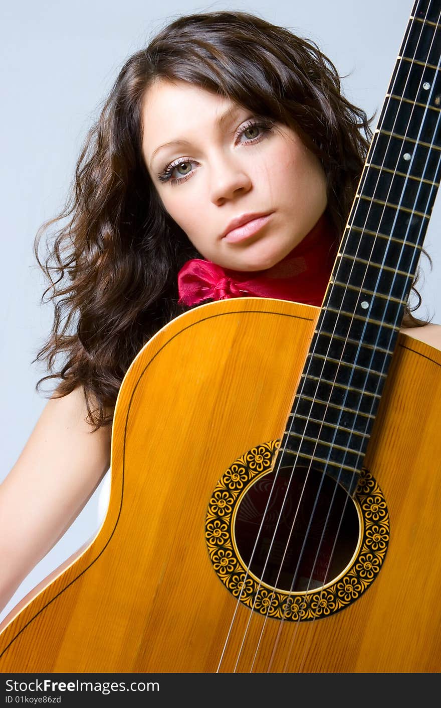 Beautiful fresh brunette with guitar in studio