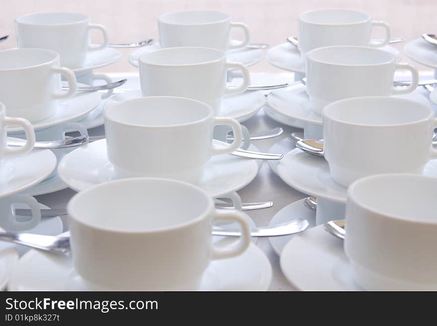 White coffee cups and saucers arranged in rows. White coffee cups and saucers arranged in rows