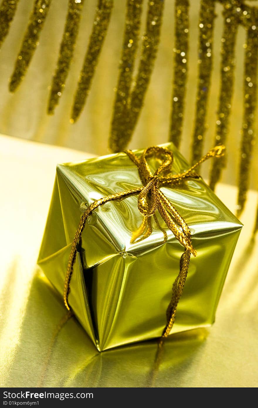 Gift box on golden background with leaf