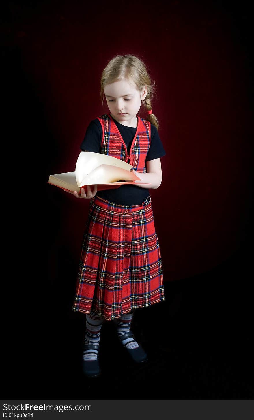 Serious schoolgirl with red book over dark. Serious schoolgirl with red book over dark