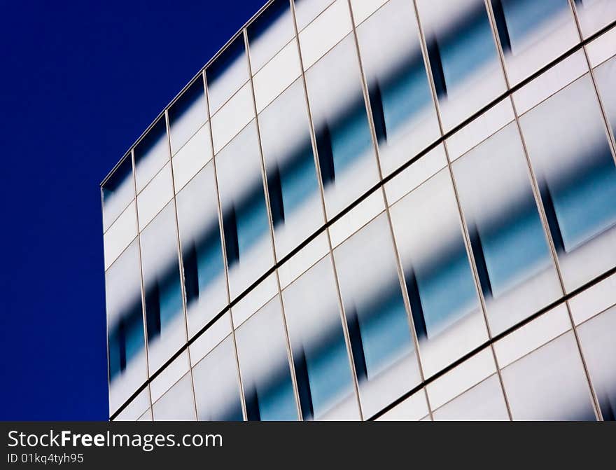 View of modern office building windows against a deep blue sky. View of modern office building windows against a deep blue sky.