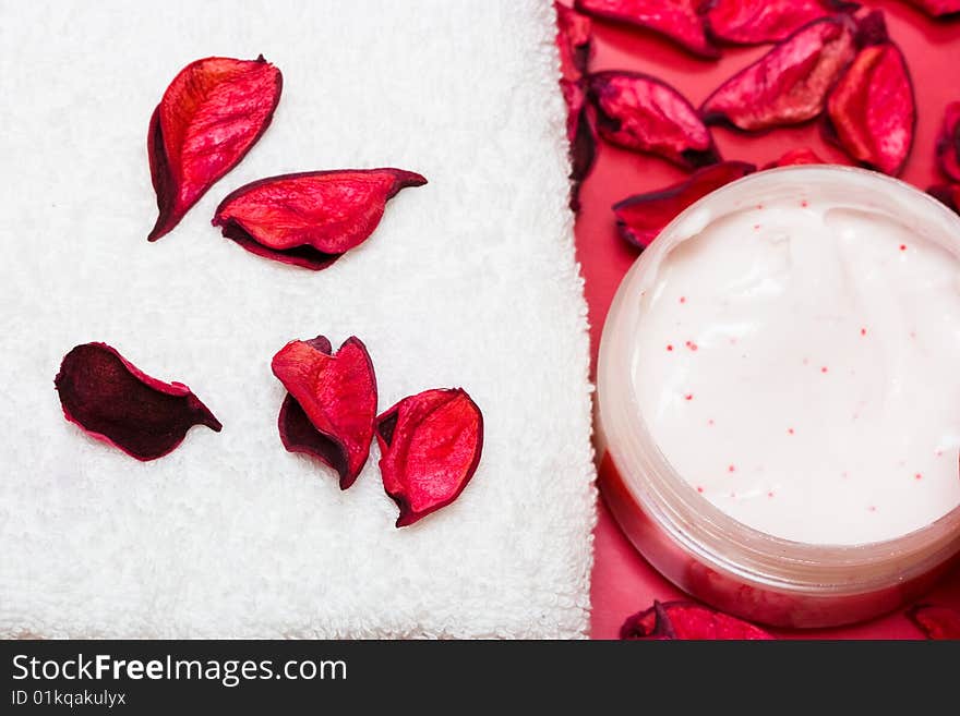 Spa essentials, cream and towel with red petals