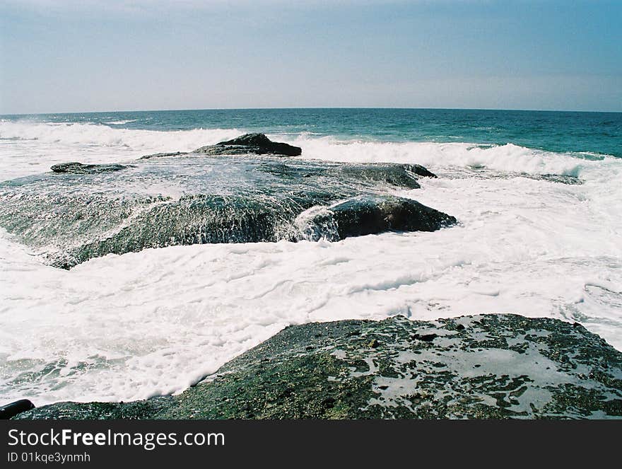 Ocean warer swallows rocks as waves roll in. Ocean warer swallows rocks as waves roll in.