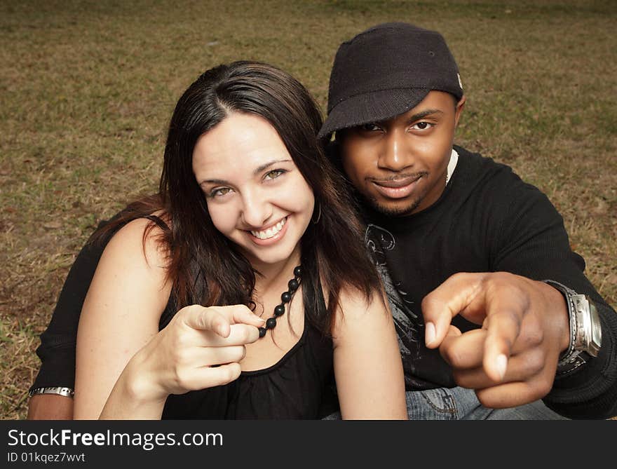 Young interracial couple pointing fingers at the camera. Young interracial couple pointing fingers at the camera