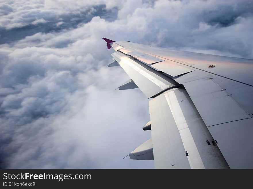 Sunrise over the clouds, high in the sky, view from the plane, with close up on the wing. Sunrise over the clouds, high in the sky, view from the plane, with close up on the wing