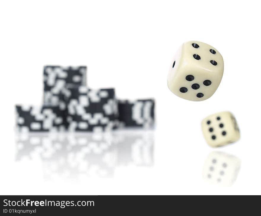 Pair of dice rolling in front of stacked black poker chips. Pair of dice rolling in front of stacked black poker chips.