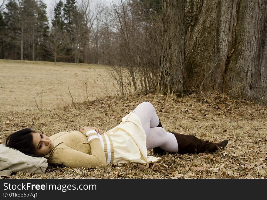 Young Indian girl is lying down next to a tree in fall. Young Indian girl is lying down next to a tree in fall.
