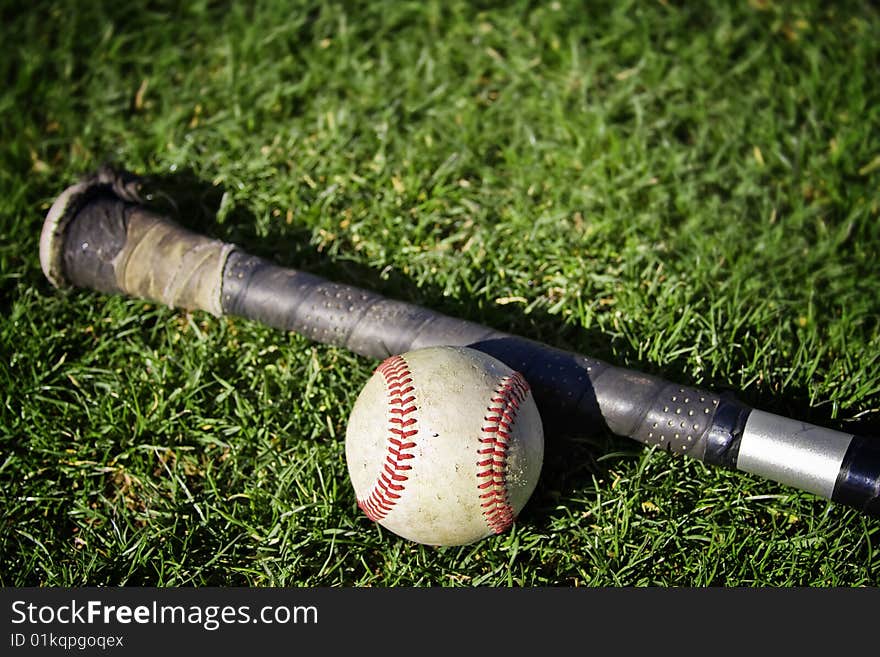 A baseball and a hat on a grassy baseball field. Shallow depth of field