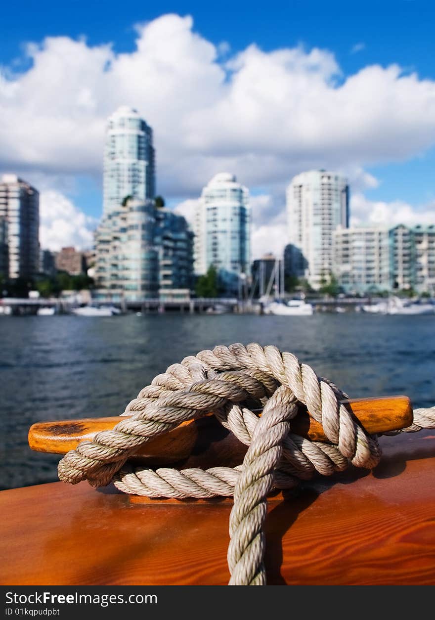 A rope is coiled around a cleat with Vancouver, B.C. cityscape in background. A rope is coiled around a cleat with Vancouver, B.C. cityscape in background.