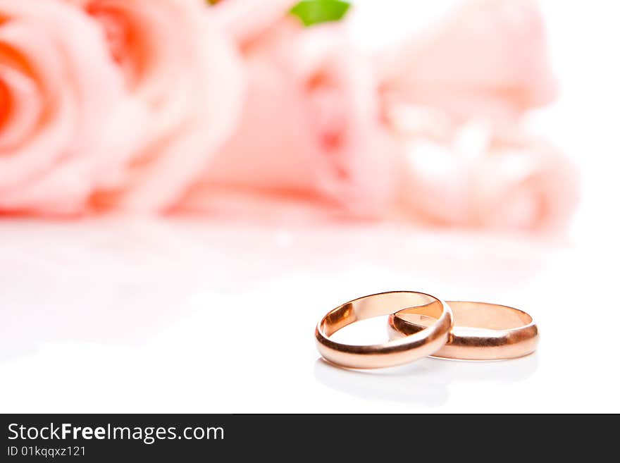 Wedding rings in front of roses, shallow focus on rings