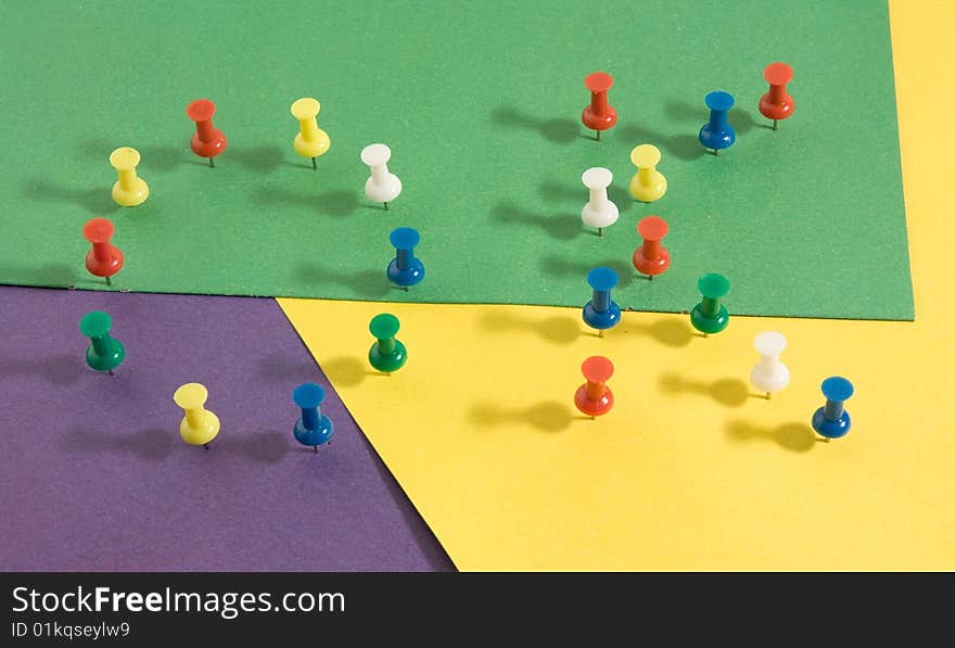 Coloured pushpins on background of a different coloured paper. Coloured pushpins on background of a different coloured paper