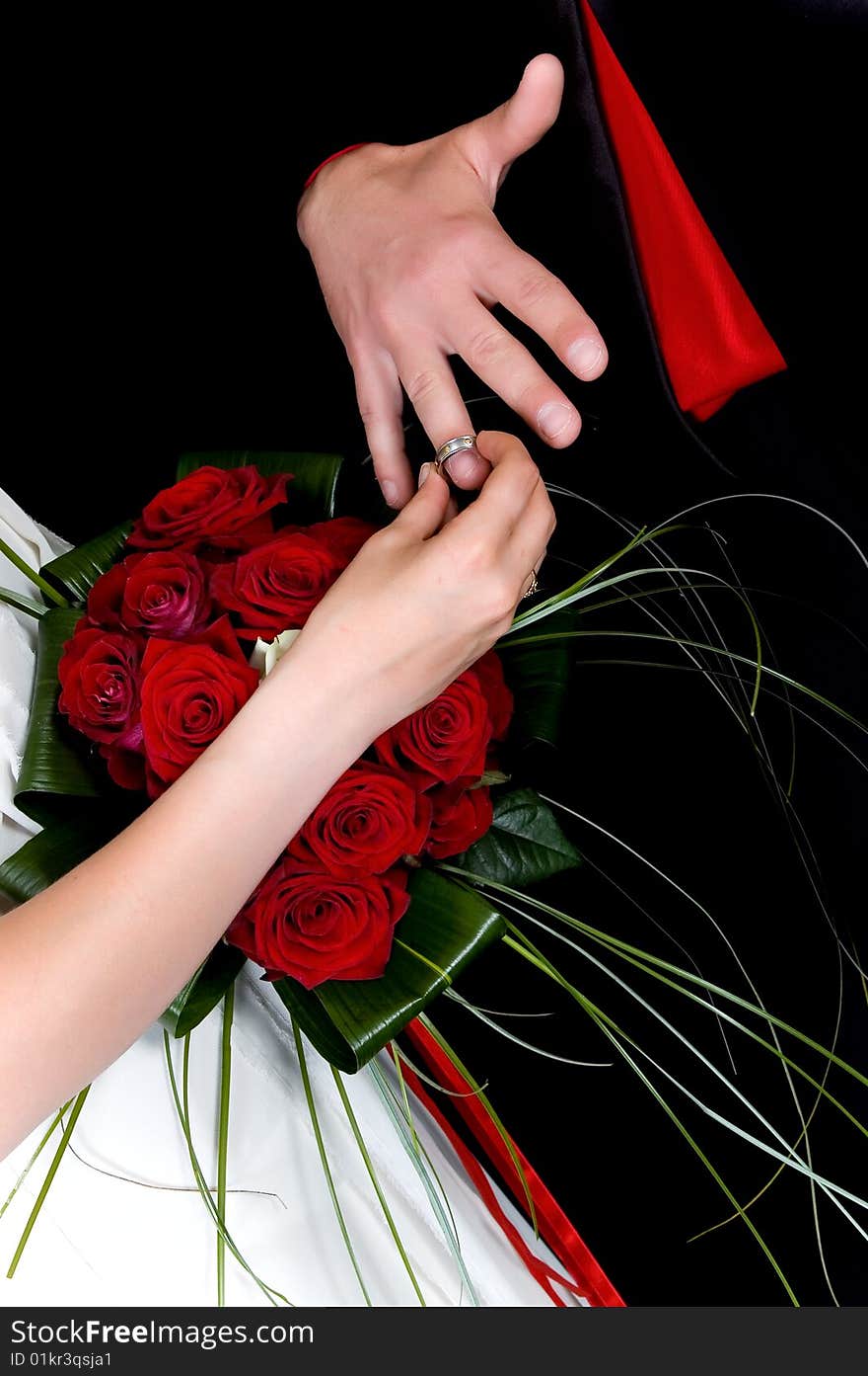 Hands over wedding bouquet with rings on black background, studio shot