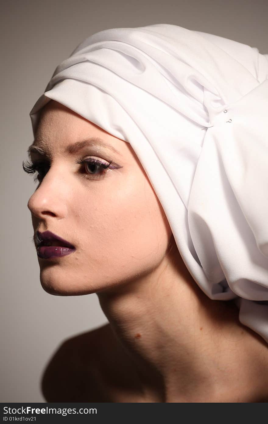 Portrait of the beautiful young woman with a bright make-up and a white fabric on a head