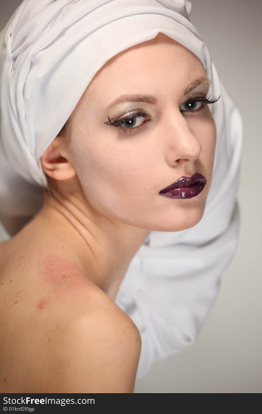 Portrait of the beautiful young woman with a bright make-up and a white fabric on a head