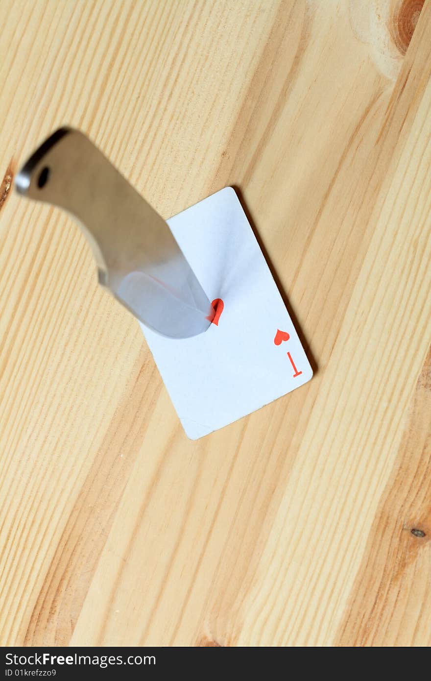 Direct hit to playing card with missile knife on wooden background