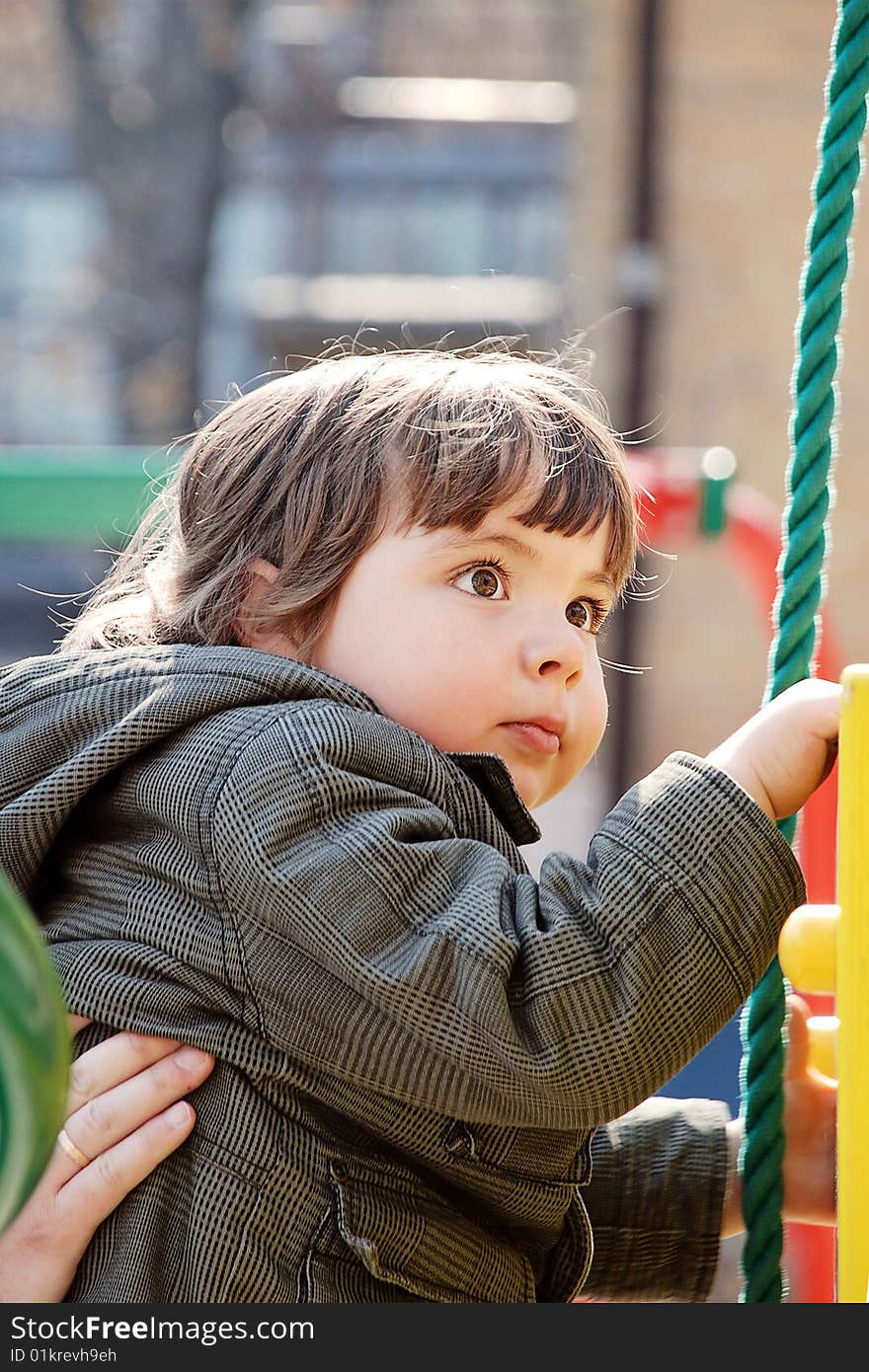 Child, carefully guarded a hand the grown man perches upstairs on a playground. Child, carefully guarded a hand the grown man perches upstairs on a playground