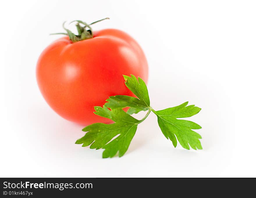 A leaf of parsley in front of a tomato. A leaf of parsley in front of a tomato.