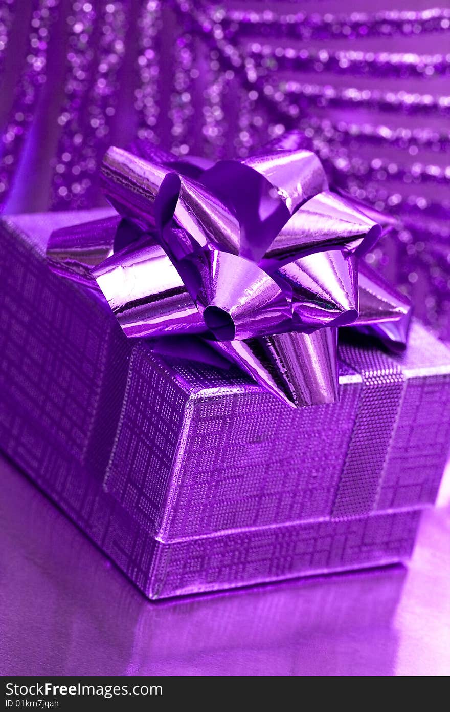 Gift box on violet background with leaf