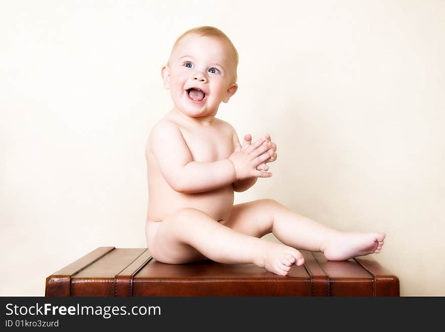 Young baby sitting on an old style suitcase