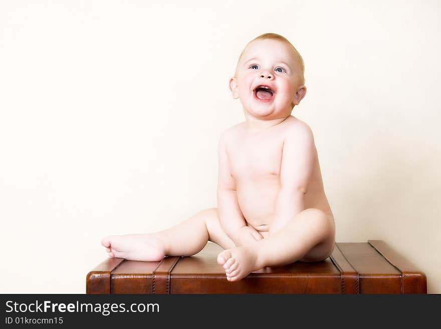 Young baby sitting on an old style suitcase