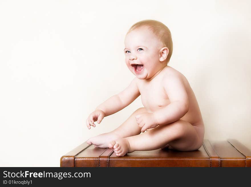 Young baby sitting on an old style suitcase