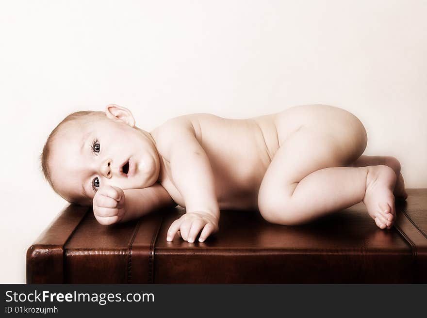 Young baby lying on his tummy on an old style suitcase