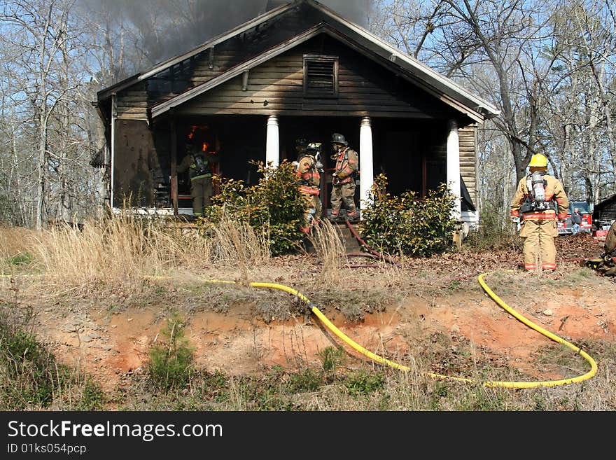 Firefighter putting out fire on house. Firefighter putting out fire on house