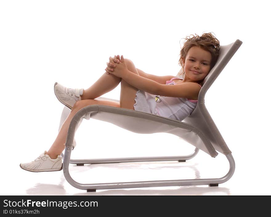 A young girl sitting in a gray chair and raised his feet. A young girl sitting in a gray chair and raised his feet