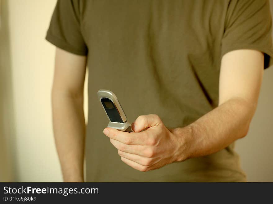 Male hands holding cell phone in front of t-Shirts. Male hands holding cell phone in front of t-Shirts