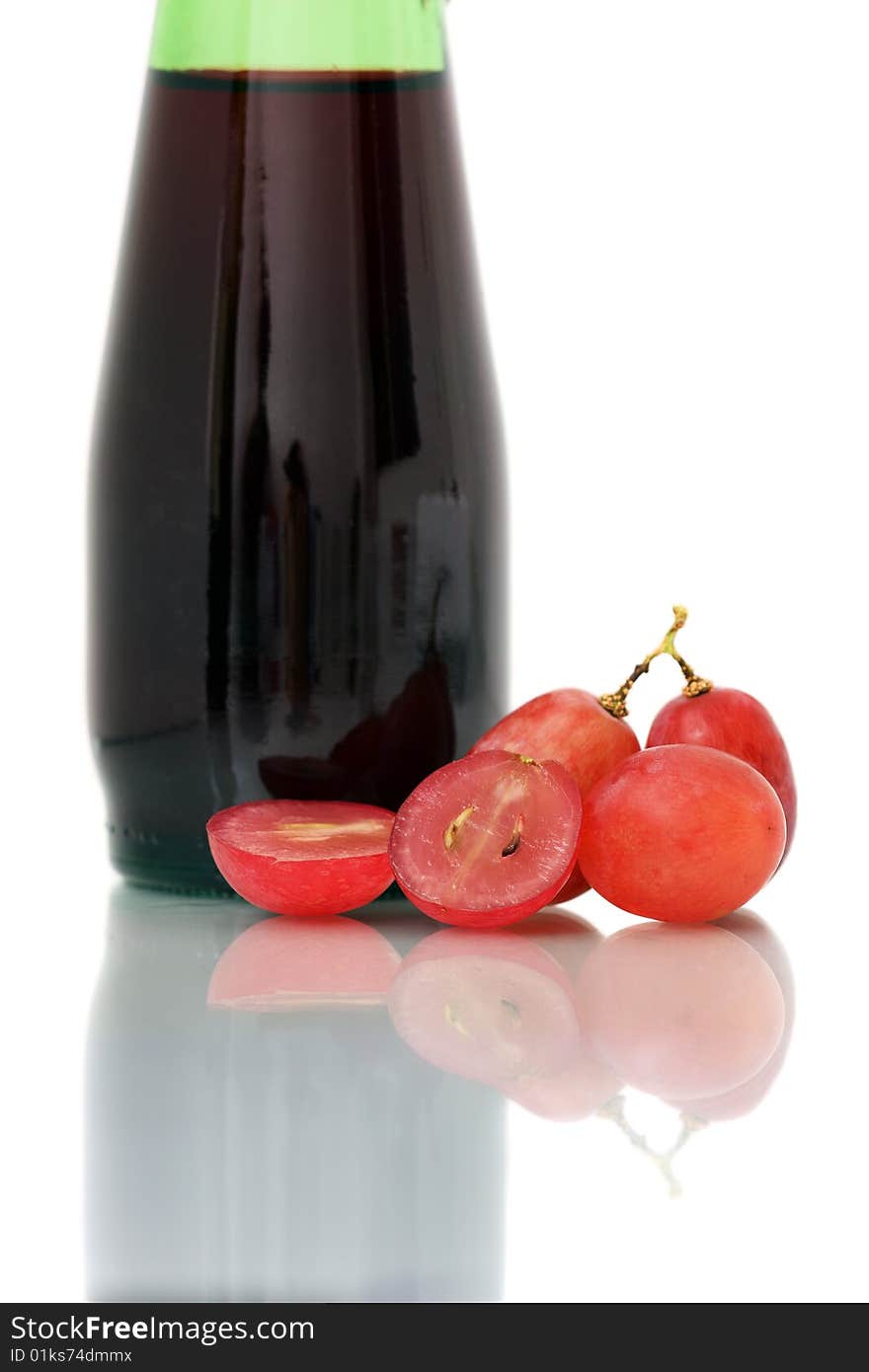 Bunch of red grapes on white plate beside wine bottle. Bunch of red grapes on white plate beside wine bottle.