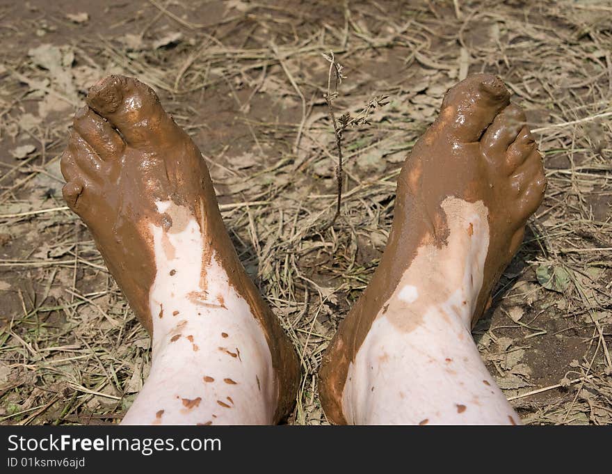 Two muddy feet over dirty grass background. Two muddy feet over dirty grass background